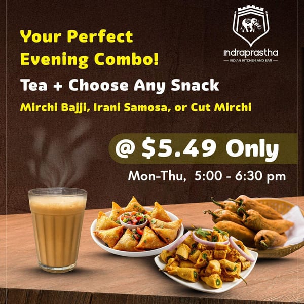 Steaming chai, samosas, mirchi bajji, and cut mirchi on a wooden table for Indraprastha's evening combo.